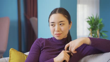 Asian-happy-woman-sitting-alone-in-living-room.